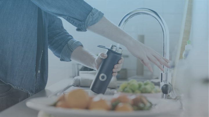 Close up of a man filling a water bottle under a tap.