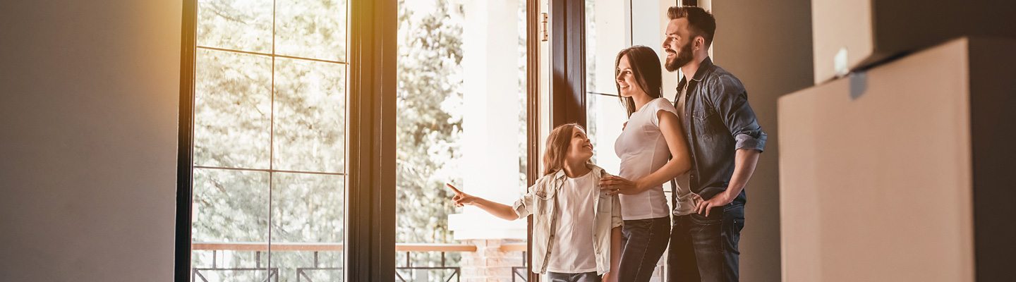 A male, female, and child standing together looking out of a french door.
