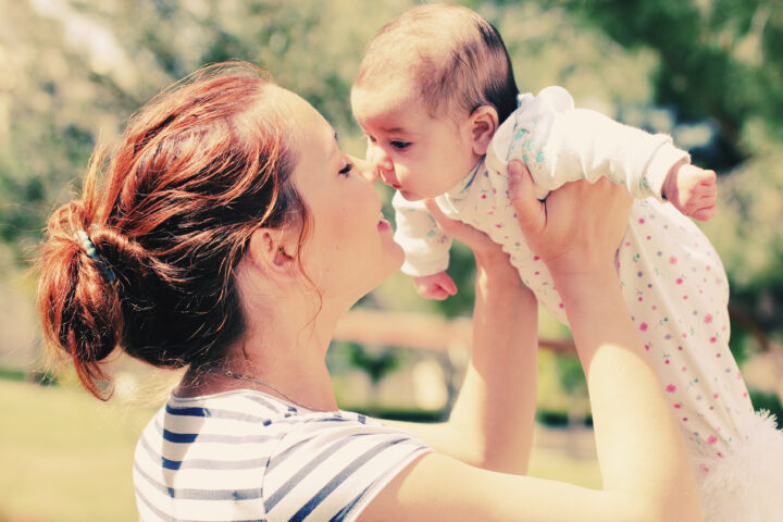 A woman holding a baby close to her face, with their noses touching. The woman is smiling.